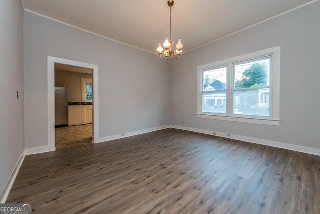 empty room featuring dark hardwood / wood-style floors, an inviting chandelier, and ornamental molding