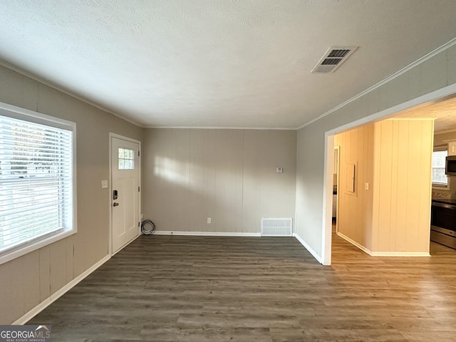 interior space featuring ornamental molding, a textured ceiling, and dark wood-type flooring