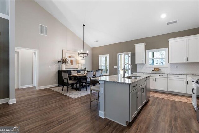 dining space with plenty of natural light, high vaulted ceiling, dark hardwood / wood-style floors, and ceiling fan with notable chandelier