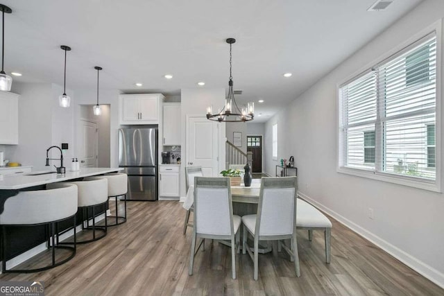 dining area with hardwood / wood-style floors, a notable chandelier, and sink