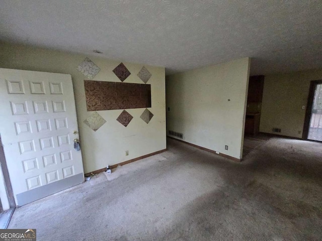 carpeted empty room featuring a textured ceiling