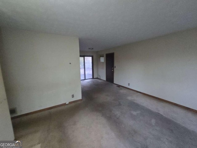 spare room with dark carpet and a textured ceiling