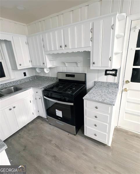 kitchen with white cabinets, light hardwood / wood-style floors, and stainless steel gas range