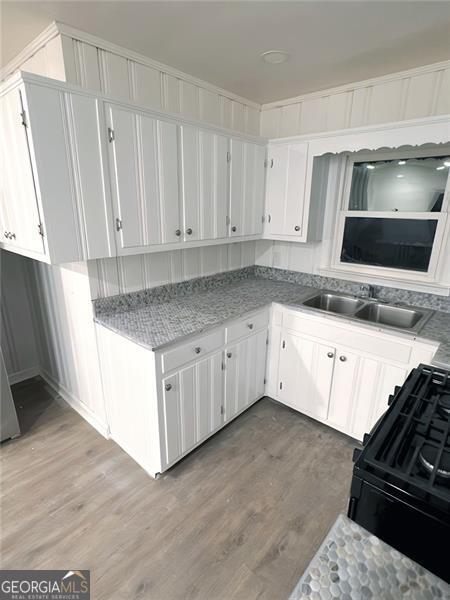 kitchen featuring white cabinets, black range oven, and sink