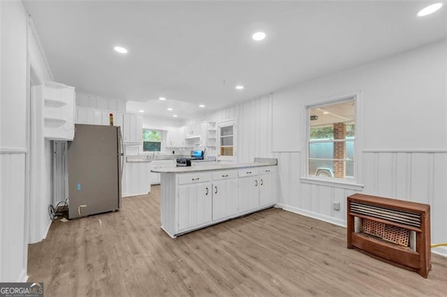 kitchen with a wealth of natural light, light hardwood / wood-style floors, white cabinetry, and appliances with stainless steel finishes