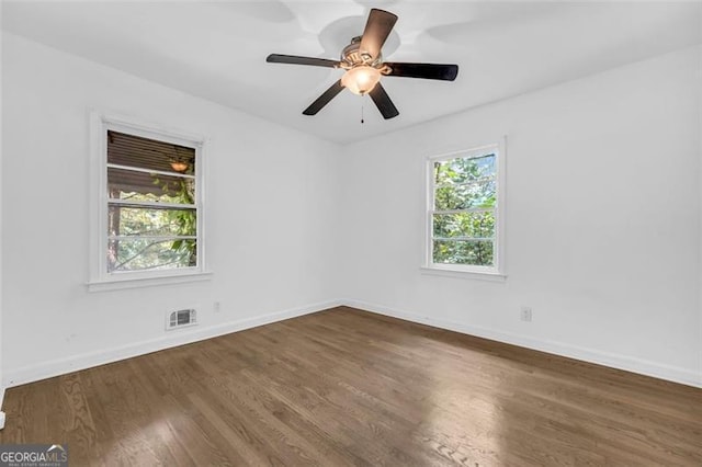 spare room with ceiling fan, a healthy amount of sunlight, and dark wood-type flooring