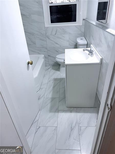 bathroom with vanity, a tub to relax in, toilet, and tile walls