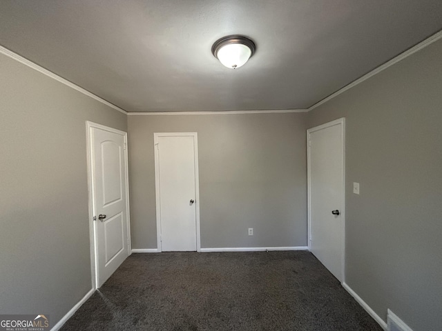 empty room featuring dark colored carpet and crown molding