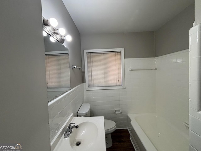 bathroom featuring toilet, hardwood / wood-style flooring, tile walls, a bath, and sink