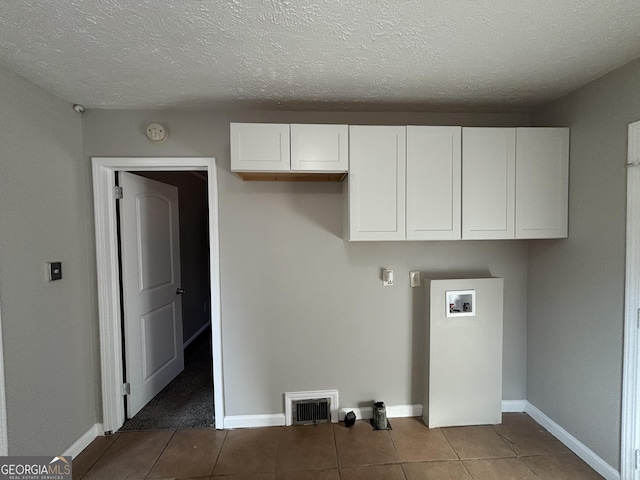 laundry room featuring washer hookup, a textured ceiling, and tile patterned floors