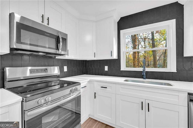 kitchen featuring appliances with stainless steel finishes, white cabinetry, and sink