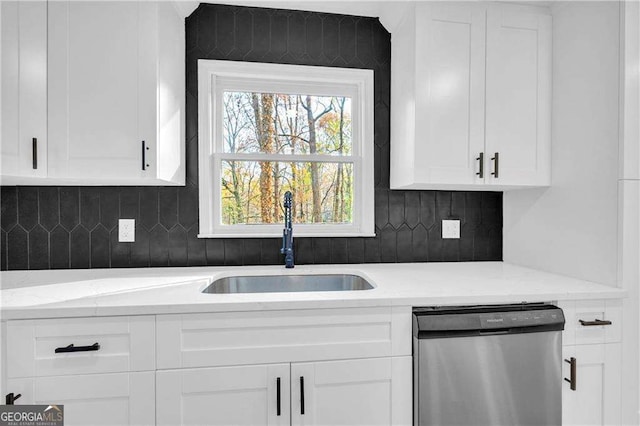 kitchen with light stone countertops, backsplash, stainless steel dishwasher, sink, and white cabinetry