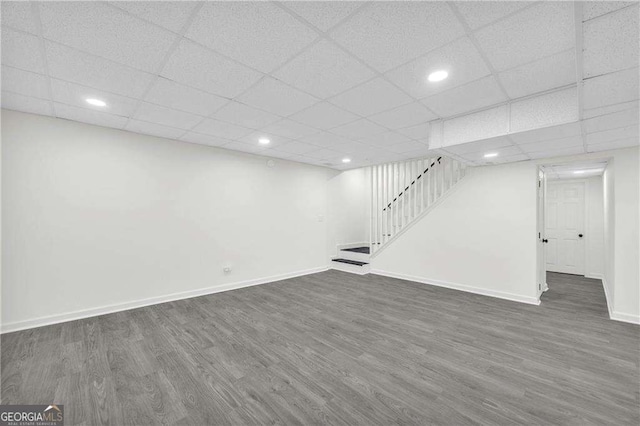 basement with a drop ceiling and dark hardwood / wood-style floors