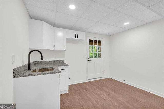 kitchen featuring sink, white cabinets, dark stone counters, and light hardwood / wood-style flooring