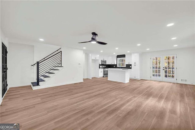 unfurnished living room with french doors, light wood-type flooring, and ceiling fan