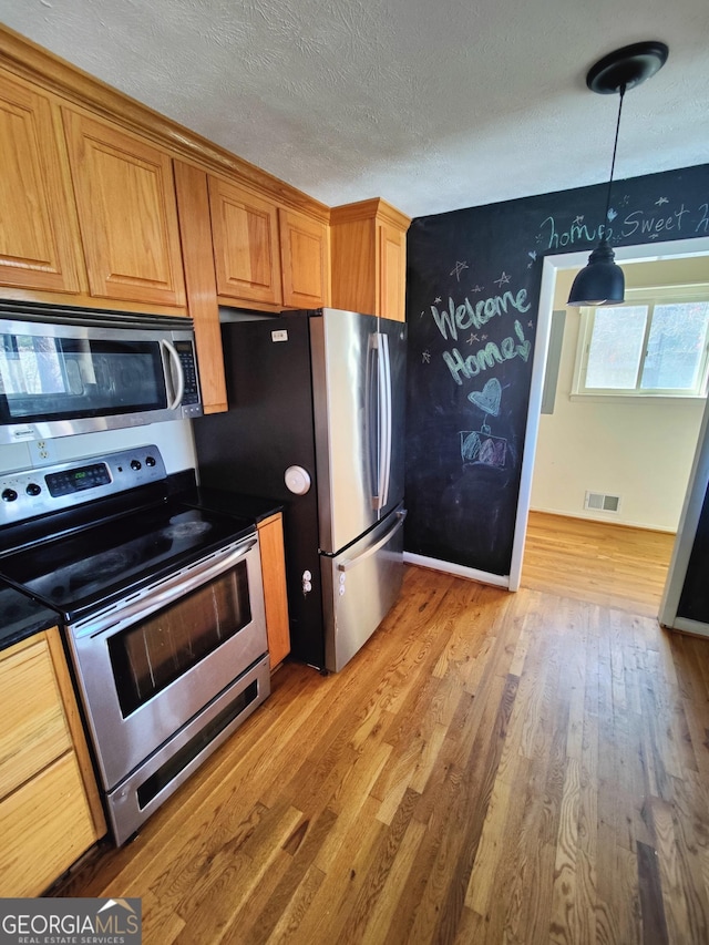 kitchen featuring hanging light fixtures, light hardwood / wood-style flooring, stainless steel appliances, and a textured ceiling