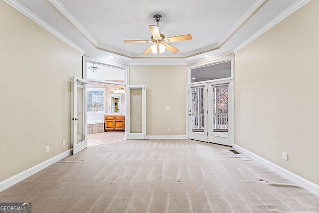 unfurnished bedroom featuring french doors, ornamental molding, a tray ceiling, light colored carpet, and ceiling fan