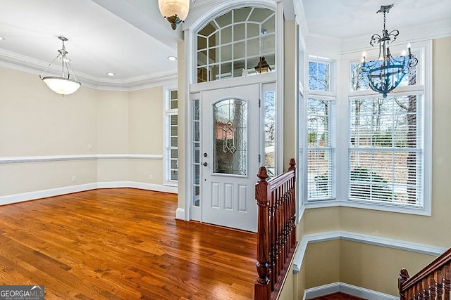 entryway with crown molding, hardwood / wood-style floors, and an inviting chandelier