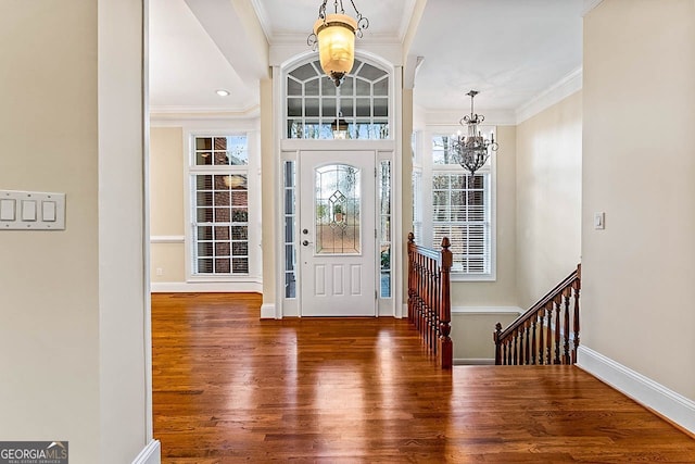 entrance foyer with crown molding, dark hardwood / wood-style floors, and an inviting chandelier