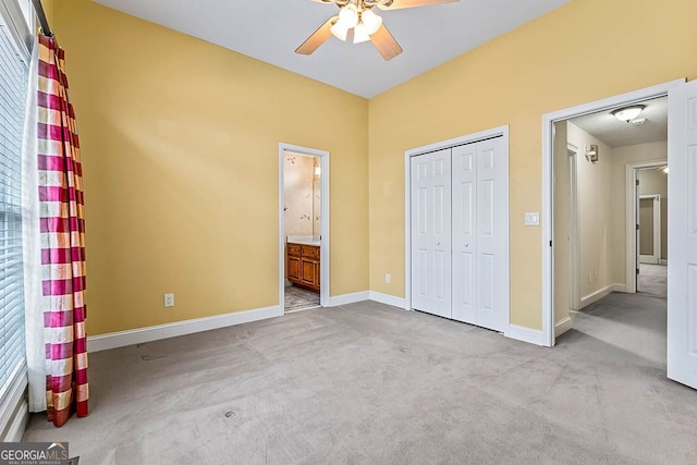 unfurnished bedroom with ceiling fan, ensuite bathroom, light colored carpet, multiple windows, and a closet