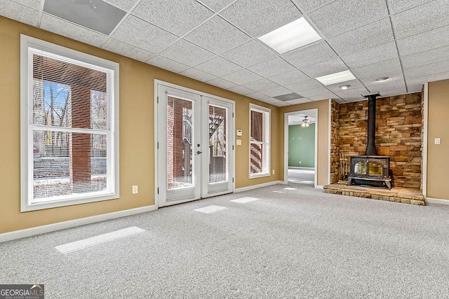 unfurnished living room with french doors, a wood stove, and a wealth of natural light