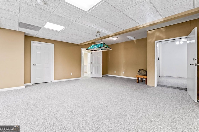 basement featuring carpet flooring and a paneled ceiling