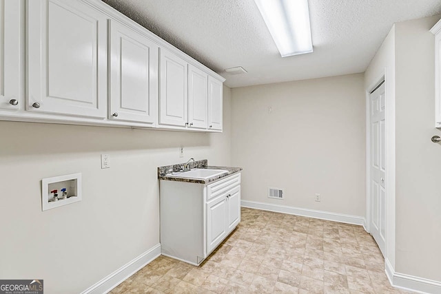 laundry room featuring cabinets, sink, washer hookup, and a textured ceiling