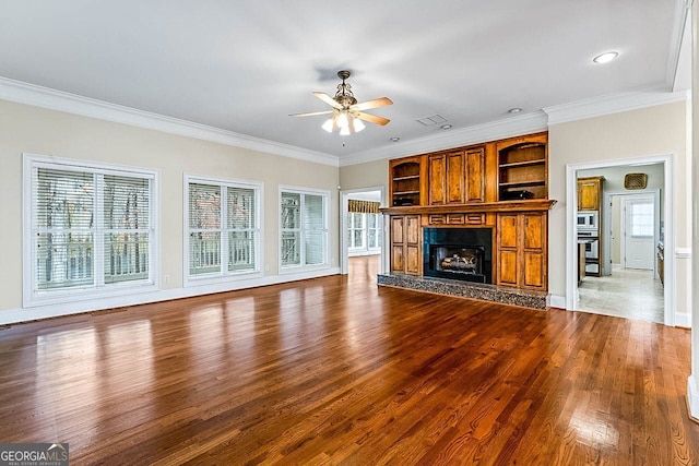 unfurnished living room featuring hardwood / wood-style flooring, plenty of natural light, ceiling fan, and ornamental molding