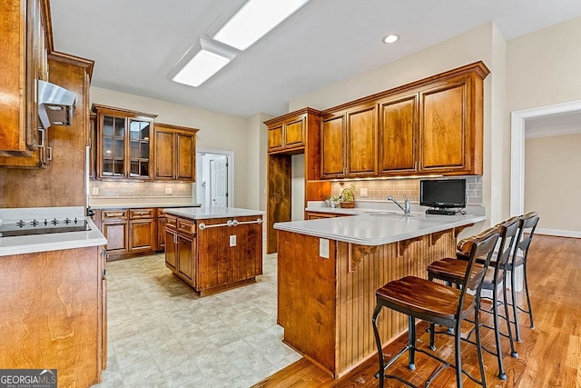 kitchen with a kitchen bar, light wood-type flooring, tasteful backsplash, and a kitchen island