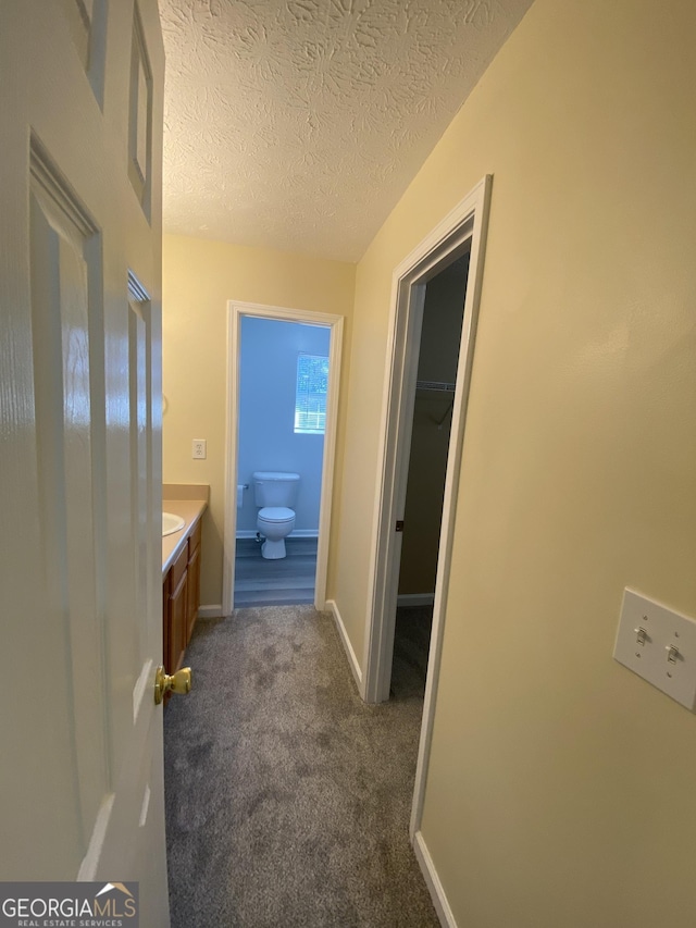 hallway with dark colored carpet and a textured ceiling