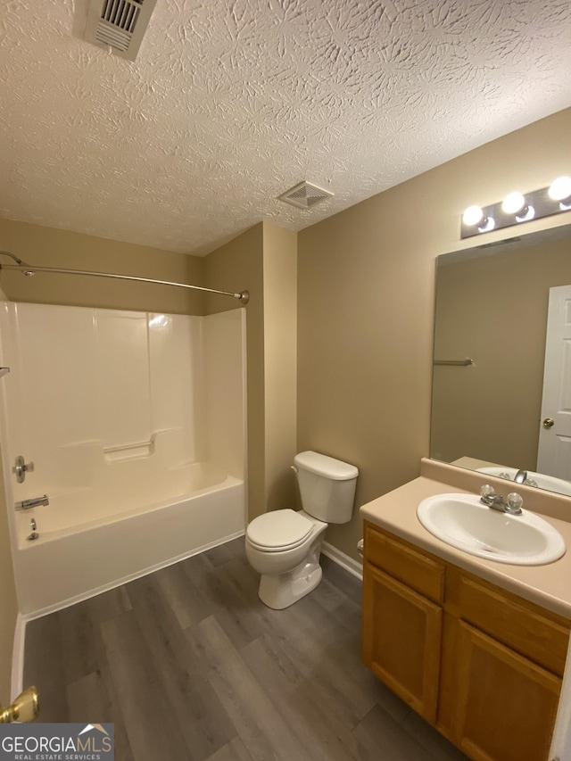 full bathroom featuring vanity, toilet, a textured ceiling, shower / bathtub combination, and wood-type flooring