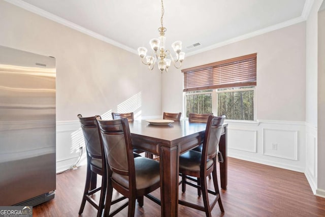 dining space with a notable chandelier, dark hardwood / wood-style flooring, and ornamental molding