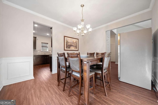 dining space featuring dark hardwood / wood-style floors, an inviting chandelier, and ornamental molding