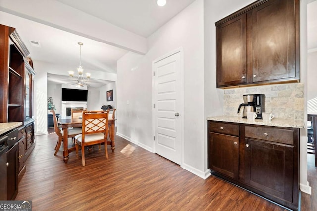 kitchen with dark hardwood / wood-style floors, light stone counters, and dark brown cabinetry