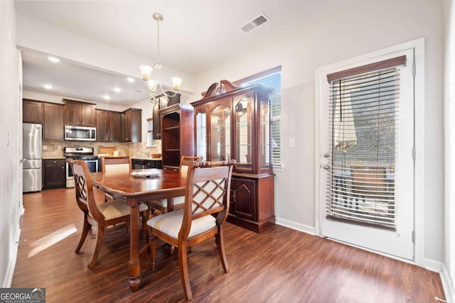 dining space with dark hardwood / wood-style floors and an inviting chandelier