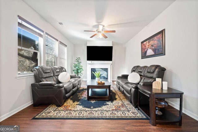 living room with dark hardwood / wood-style floors, ceiling fan, and a fireplace