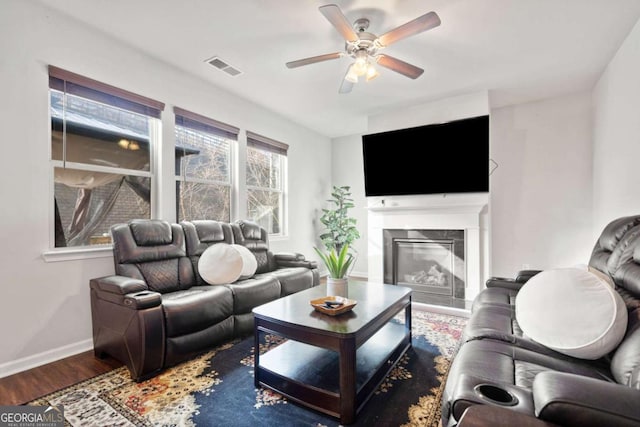 living room featuring a premium fireplace, hardwood / wood-style floors, and ceiling fan