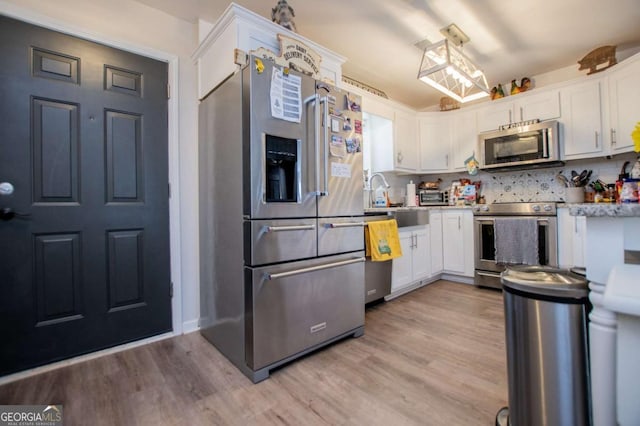 kitchen featuring backsplash, white cabinets, sink, light hardwood / wood-style flooring, and stainless steel appliances