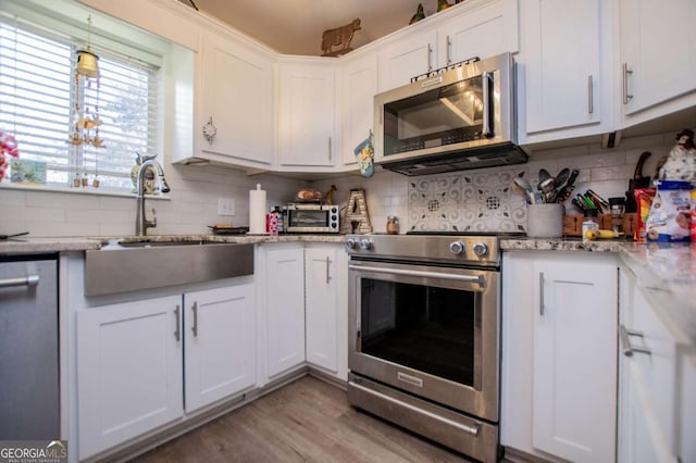 kitchen featuring light stone counters, sink, white cabinets, and stainless steel appliances