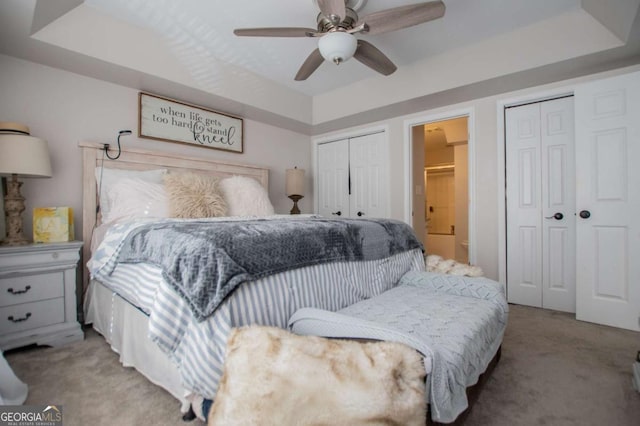 bedroom with a tray ceiling, ceiling fan, and light carpet