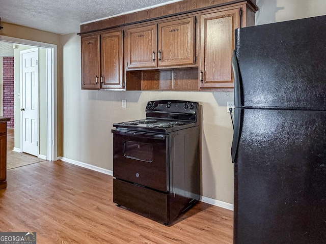 kitchen featuring a textured ceiling, light hardwood / wood-style floors, and black appliances