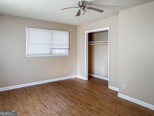 unfurnished bedroom featuring ceiling fan, a closet, dark hardwood / wood-style flooring, and a textured ceiling