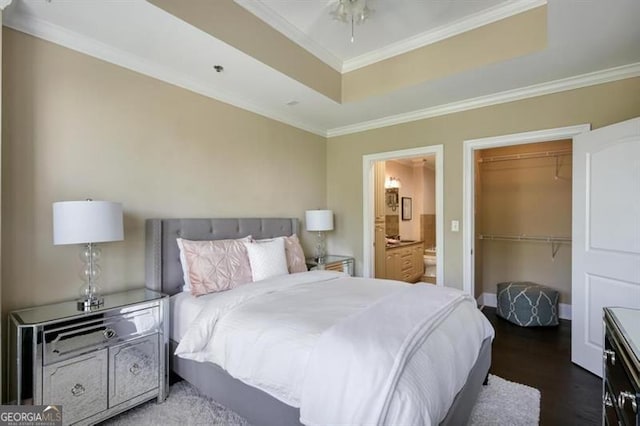 bedroom featuring a walk in closet, crown molding, connected bathroom, dark hardwood / wood-style floors, and a closet