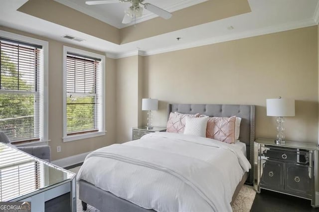 bedroom with ornamental molding, a raised ceiling, visible vents, and baseboards