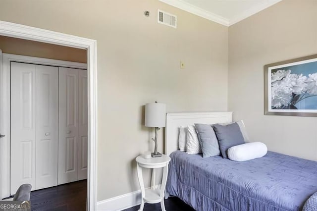 bedroom featuring a closet, visible vents, dark wood-type flooring, ornamental molding, and baseboards