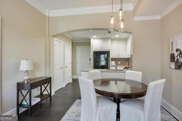 dining area featuring baseboards, ornamental molding, dark wood finished floors, and arched walkways