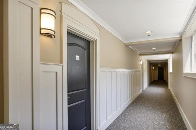 hall featuring carpet floors, ornamental molding, wainscoting, and baseboards