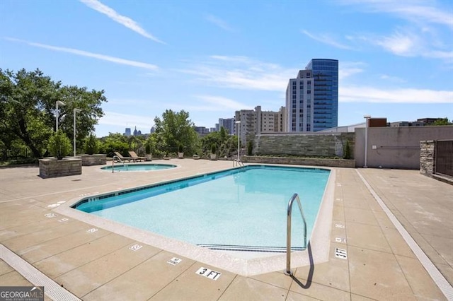 pool featuring a view of city, a community hot tub, and a patio area