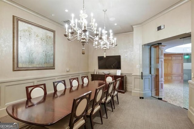 dining space featuring crown molding, carpet floors, wainscoting, and a decorative wall