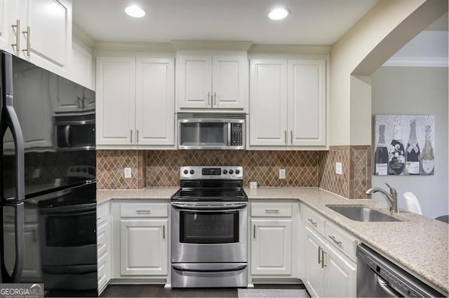 kitchen featuring stainless steel appliances, white cabinetry, a sink, and tasteful backsplash